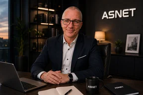 Jurand Baranowski, dyrektor działu handlowego ASNET, przy biurku w gabinecie