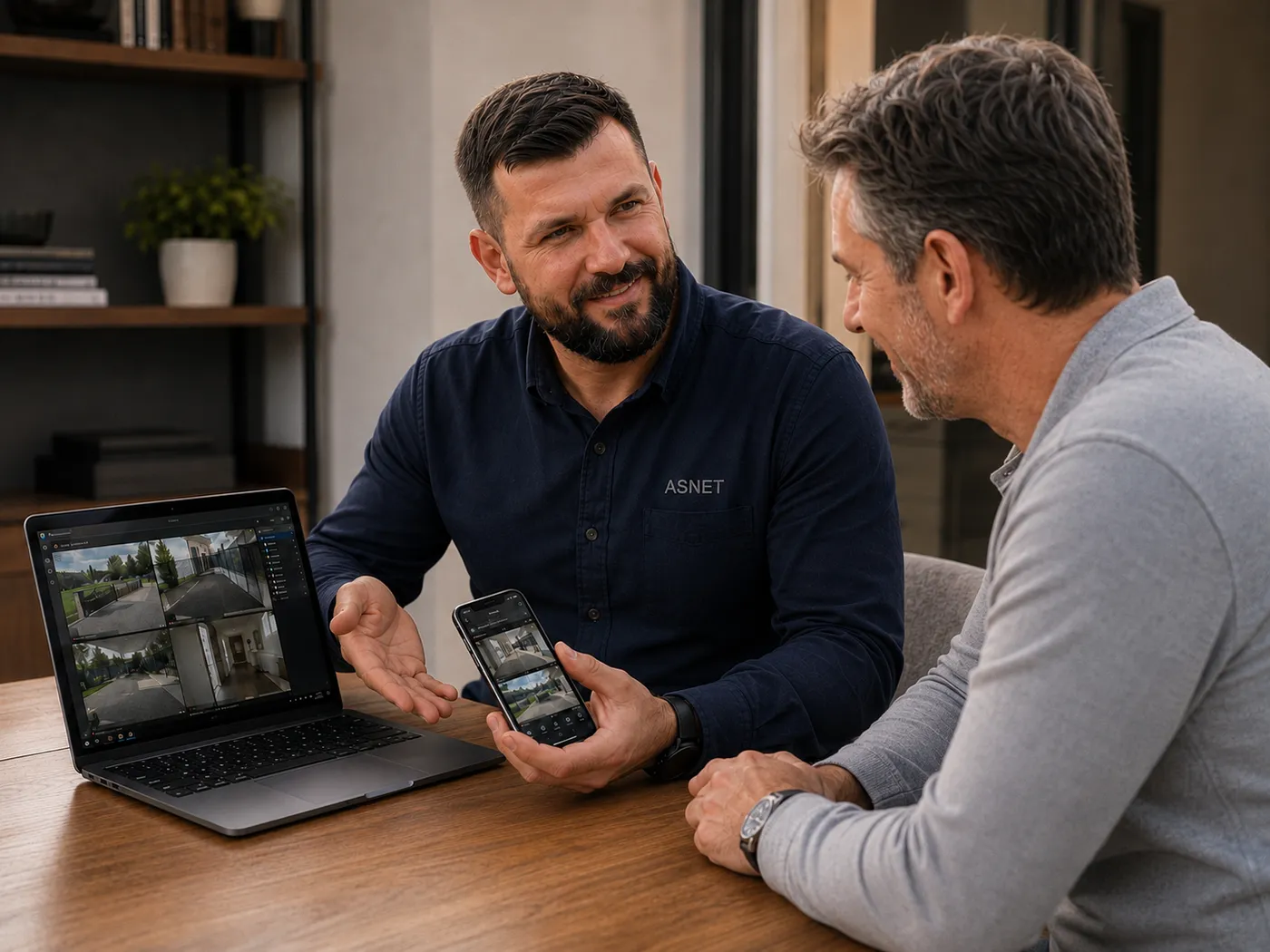 Doradca techniczny ASNET pokazuje klientowi podgląd z kamer na laptopie i w telefonie